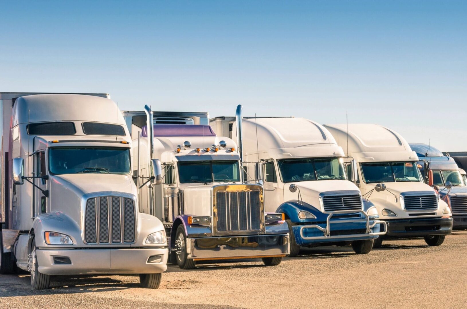 A row of semi trucks parked in a lot.