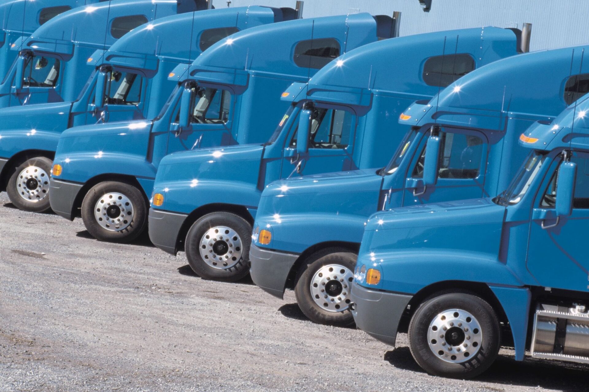 A row of blue semi trucks parked in a lot.
